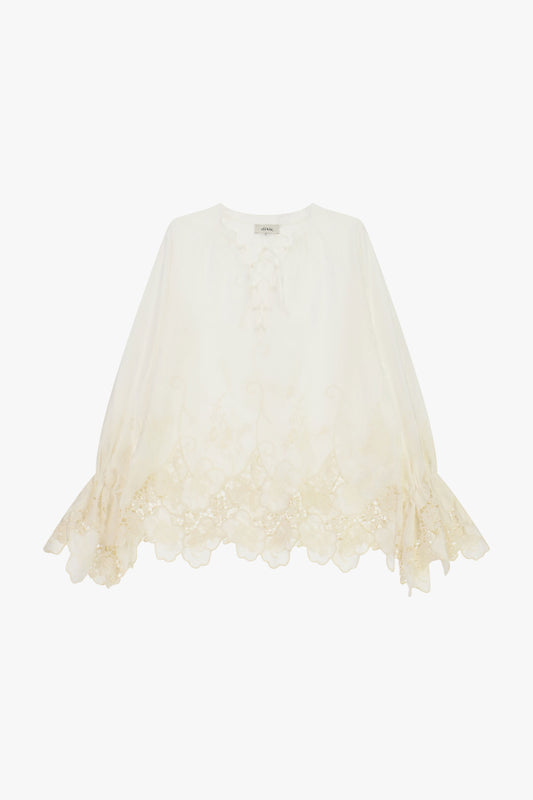 Blusa ampia con ricami floreali e bordo smerlato